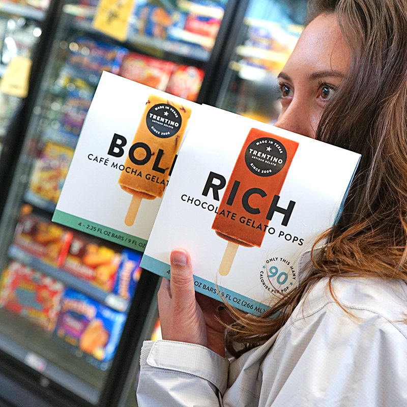 A shopper holding the Bold and Rich Trentino gelato pops boxes in front of the freezer aisle